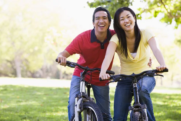 Couple on bikes outdoors smiling — Stock Photo, Image