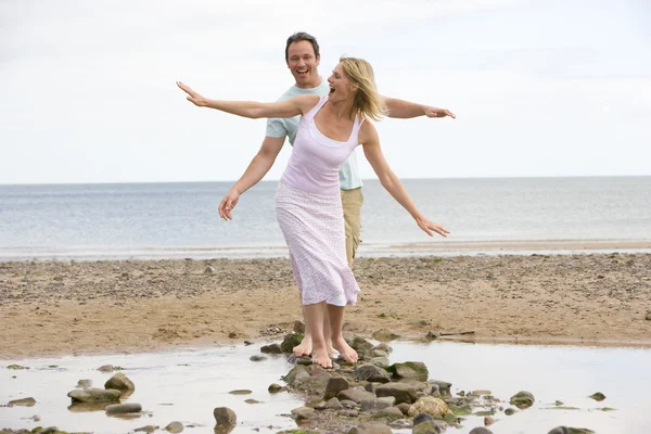 石の上を歩いて 笑顔のビーチでのカップル — ストック写真
