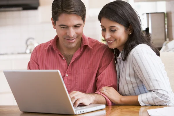 Par i köket med laptop leende — Stockfoto