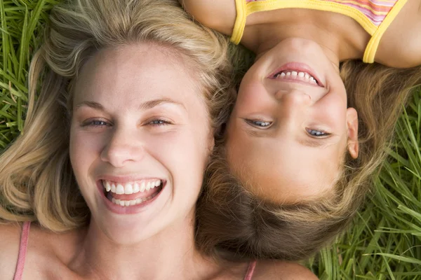 Kvinna och unga flickan liggande i gräset skrattar — Stockfoto
