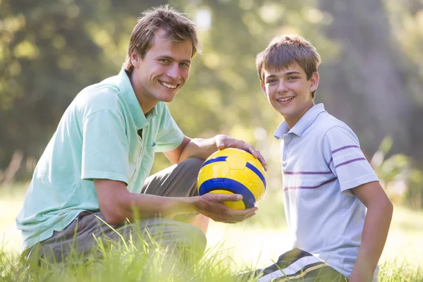 Muž a mladá kluk, venku s úsměvem a fotbalový míč — Stock fotografie