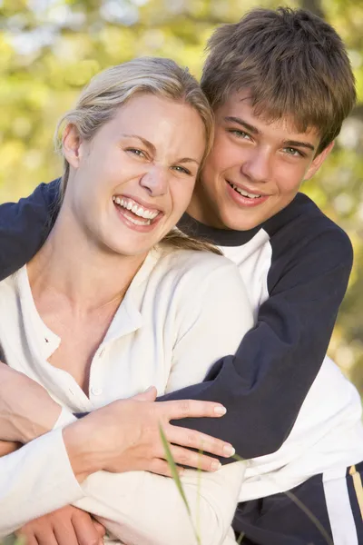 Mujer y chico joven abrazando al aire libre y sonriendo —  Fotos de Stock