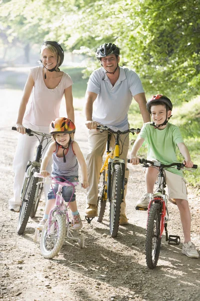 Семья сидит на велосипедах на дорожке улыбаясь — стоковое фото