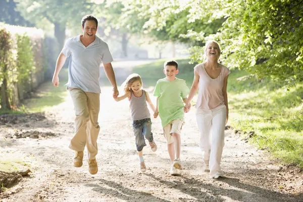 Família correndo ao ar livre de mãos dadas e sorrindo — Fotografia de Stock