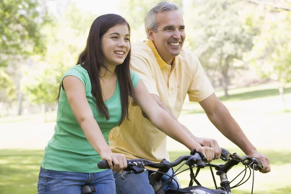 Мужчина и девушка на велосипедах на улице улыбаются — стоковое фото