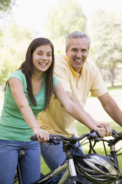 Чоловік і дівчина на велосипедах на відкритому повітрі посміхаються — стокове фото