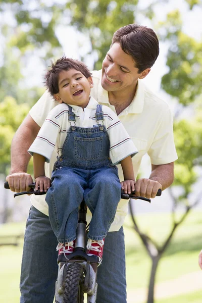 Man and young boy on a bike outdoors smiling — Stock Photo, Image