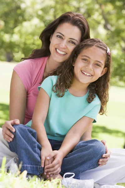 女人和年轻女孩坐在户外微笑 — 图库照片