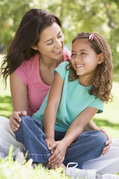 女人和年轻女孩坐在户外微笑 — 图库照片