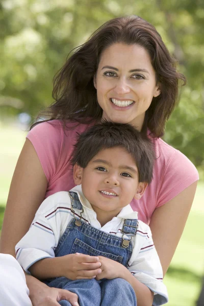 Kobieta i młody chłopak siedzący na zewnątrz uśmiechający się — Zdjęcie stockowe