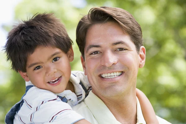 Homem e menino abraçando ao ar livre sorrindo — Fotografia de Stock