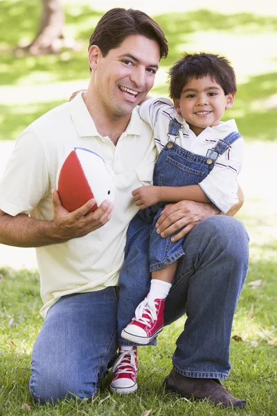 Man and young boy outdoors with football smiling — Stock Photo, Image