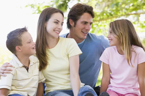 Familia sentada al aire libre sonriendo — Foto de Stock