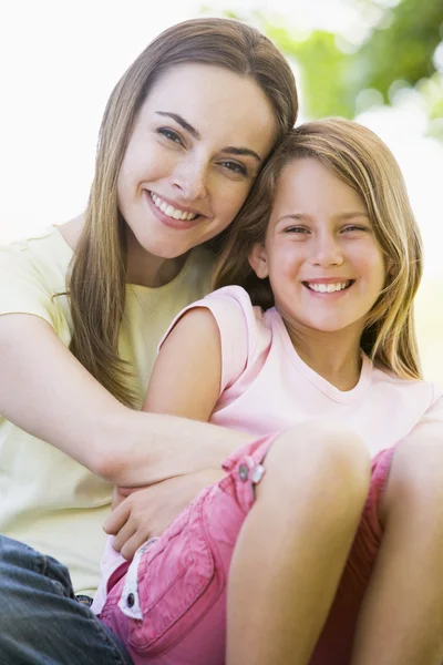 Vrouw en jonge meisje buitenshuis omarmen en glimlachen — Stockfoto