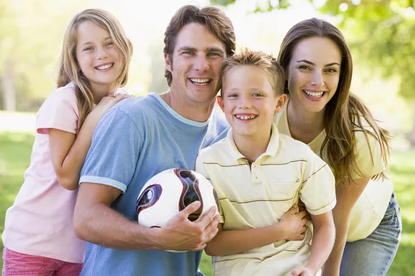 Сім'я, що стоїть на відкритому повітрі, тримає волейбол посміхаючись — стокове фото