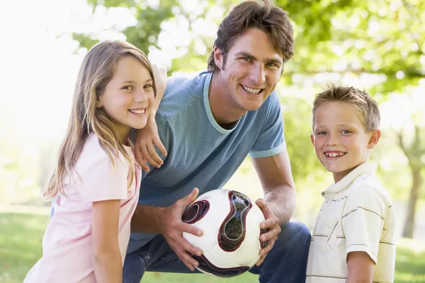 Мужчина и двое маленьких детей на открытом воздухе с волейболом и улыбкой — стоковое фото
