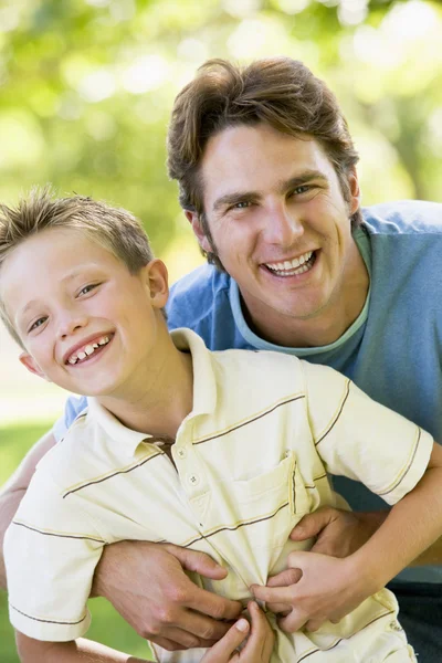 Człowiek i młody chłopak na zewnątrz Ogarnięcie i uśmiechając się — Zdjęcie stockowe