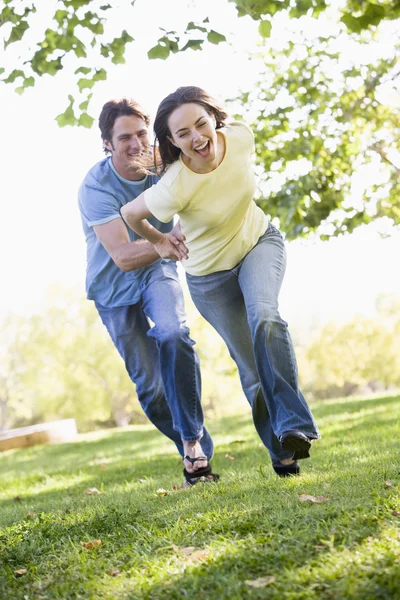 Couple running outdoors holding hands and smiling — Stock Photo, Image