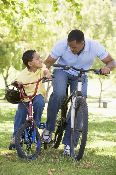 Mann und kleiner Junge auf Fahrrädern im Freien lächeln — Stockfoto