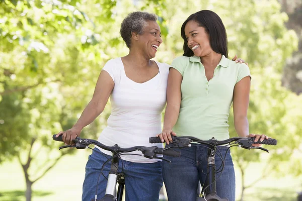 Две женщины на велосипедах на улице улыбаются — стоковое фото