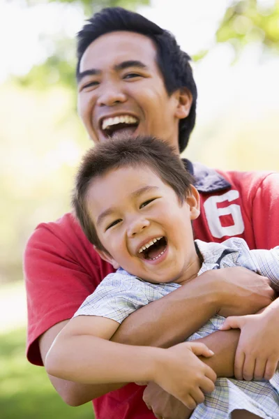 Man and young boy outdoors embracing and smiling — Stock Photo, Image