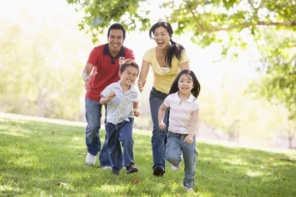 Familia corriendo al aire libre sonriendo — Foto de Stock