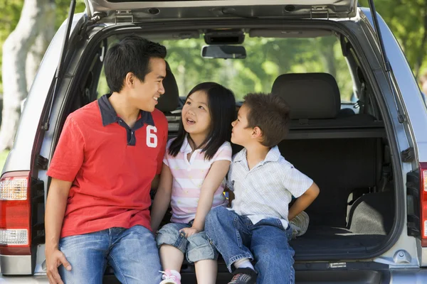 Человек с двумя детьми, сидящий на заднем сиденье фургона и улыбающийся — стоковое фото