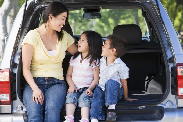 Mujer con dos niños sentados en la parte trasera de la camioneta sonriendo — Foto de Stock