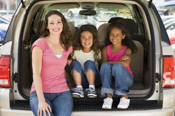 Mulher com duas meninas sentadas na parte de trás da van sorrindo — Fotografia de Stock