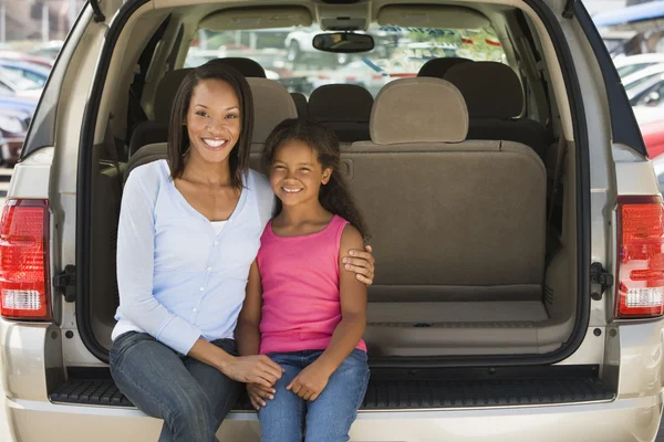 Mujer con chica joven sentada en la parte trasera de la camioneta sonriendo —  Fotos de Stock