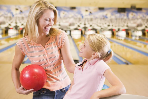 Woman and young girl in bowling alley holding ball and smiling — Stock Photo, Image