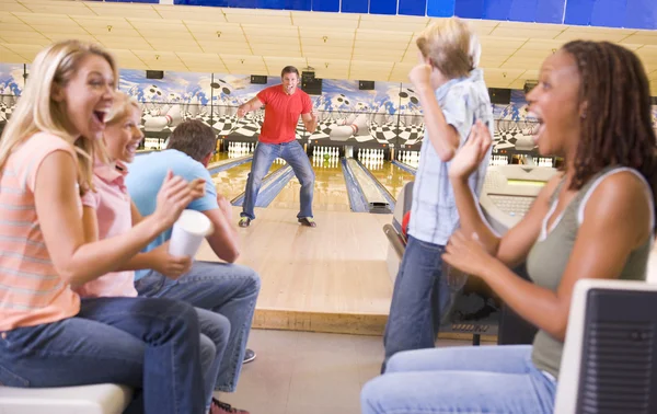 Family in bowling alley with two friends cheering and smiling — Stock Photo, Image
