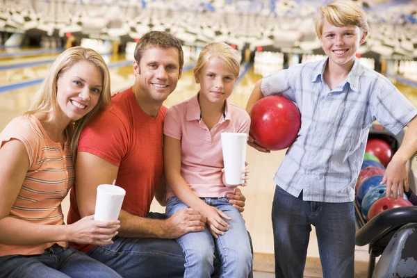 Famille au bowling avec boissons souriantes — Photo