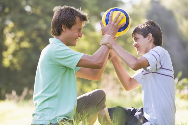 屋外サッカー ボールを保持し 笑みを浮かべて男と若い少年 — ストック写真
