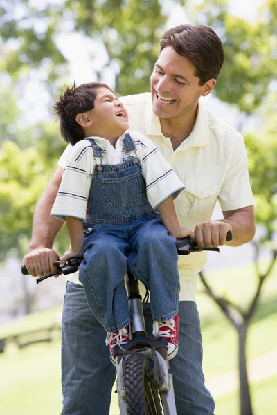 Man and young boy on a bike outdoors smiling — Stock Photo, Image