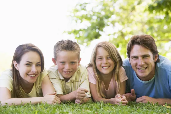 Rodina ležící venku s úsměvem — Stock fotografie