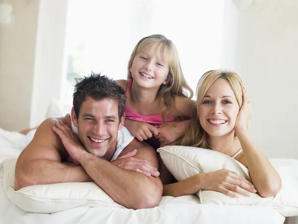 躺在床上微笑的家庭 — 图库照片