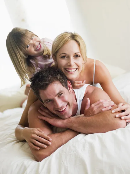 Aile oynama ve gülümseyerek yatakta — Stok fotoğraf