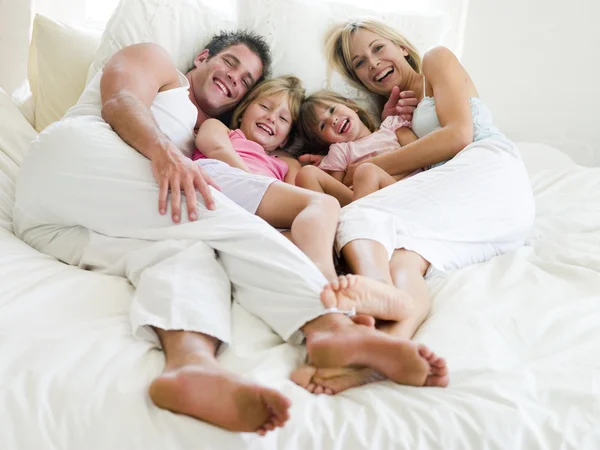 笑みを浮かべてベッドで横になっている家族 — ストック写真