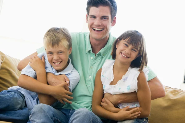Мужчина и двое маленьких детей в гостиной улыбаются — стоковое фото