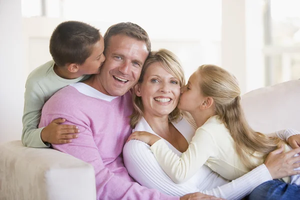坐在客厅里亲吻和微笑的家庭 — 图库照片