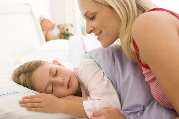 Woman waking young girl in bed smiling — Stock Photo, Image