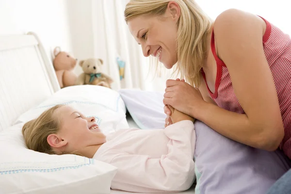 Vrouw met jonge meisje in bed glimlachen — Stockfoto