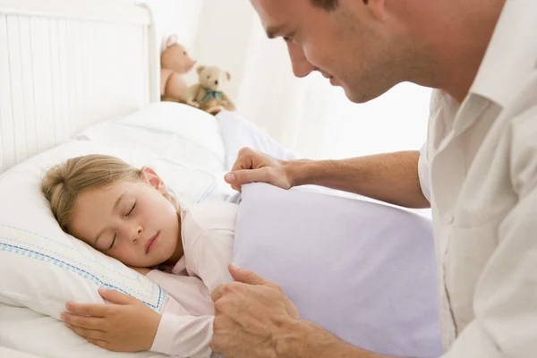 Mann weckt junges Mädchen im Bett lächelnd — Stockfoto