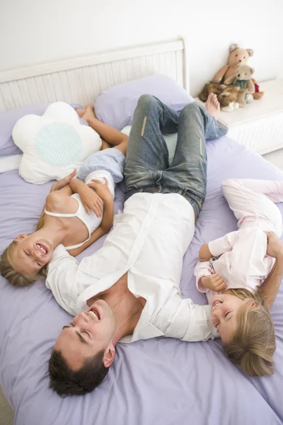 Hombre acostado en la cama con dos chicas jóvenes sonriendo —  Fotos de Stock