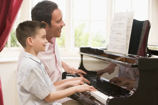 Man and young boy playing piano and smiling — Stock Photo, Image