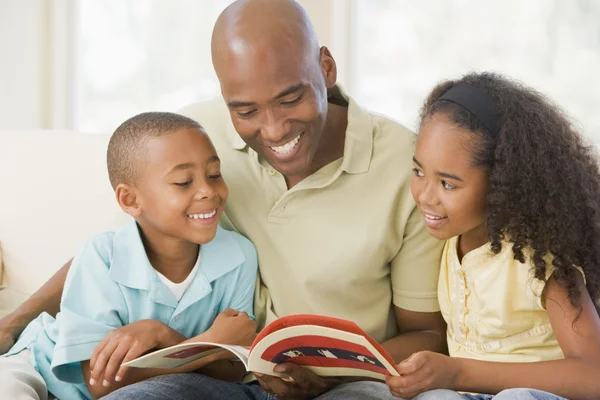 Homme et deux enfants assis dans le salon lecture livre et smi — Photo