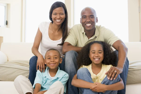 Familjen sitter i vardagsrummet leende — Stockfoto