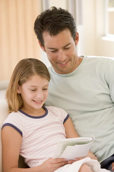 Man en jonge meisje in woonkamer lezen van boek en glimlachen — Stockfoto