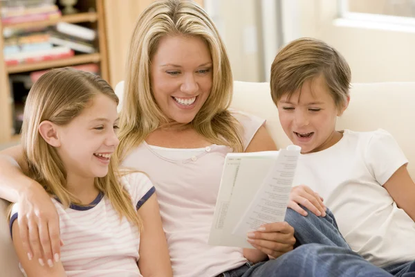 Mulher e duas crianças na sala de estar leitura livro e smi — Fotografia de Stock